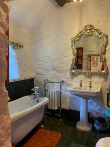 La salle de bains est pourvue d'un lavabo, d'une baignoire et d'un miroir. dans l'établissement Cozy Cottage - Near Brew Pub / Snowdonia National Park., à Caernarfon