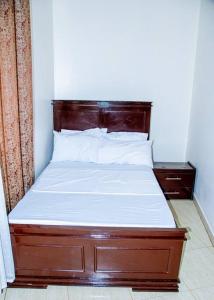 a bed with a wooden headboard in a room at Happiness at the center of the town morogoro in Morogoro