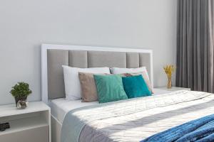 ein weißes Schlafzimmer mit einem großen Bett mit bunten Kissen in der Unterkunft Apart Astana, Комплекс Парасат, 279, рядом с Ботаническим садом in Astana