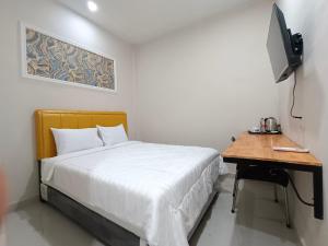 um quarto com uma cama e uma secretária com uma televisão em Grand Mulia Hotel Kisaran em Kisaran
