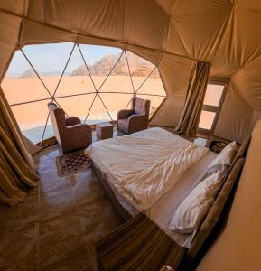 a bedroom with a bed and two chairs in a tent at Wadi Rum Ali Bubble camp in Wadi Rum