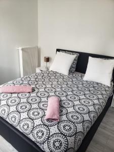- un lit avec des oreillers roses et une couverture noire et blanche dans l'établissement Vierzon superbe appartement, à Vierzon