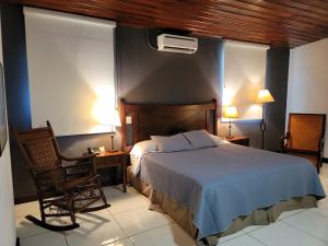 a bedroom with a bed and a chair and two lamps at Hotel Casa del Sol in Managua +83 photos
