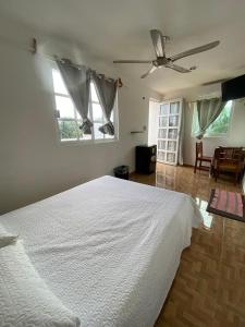 um quarto com uma cama branca e 2 janelas em Casa ka'an em Isla Mujeres