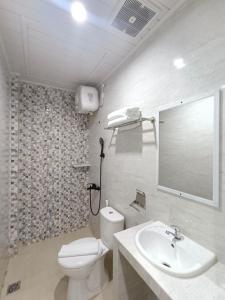 uma casa de banho com um WC, um lavatório e um espelho. em Grand Mulia Hotel Kisaran em Kisaran