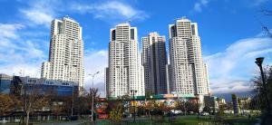 a group of tall white buildings in a city at 19th Floor Secure Condo with Pool, Fitness, Parking Included in Price in Skopje