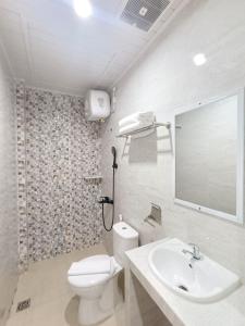 uma casa de banho com um WC, um lavatório e um espelho. em Grand Mulia Hotel Kisaran em Kisaran
