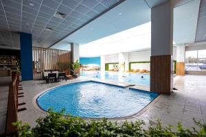 a large swimming pool in a hotel lobby at 19th Floor Secure Condo with Pool, Fitness, Parking Included in Price in Skopje