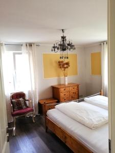 a bedroom with a bed and a chair and a chandelier at Ferienwohnung Rotenfels in Gaggenau