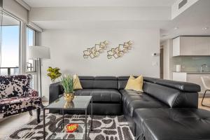 a living room with a black leather couch at NEW! 34th FL High Rise, PRIME Location, Downtown Near Stampede & Saddledome, FREE Wine & More! in Calgary