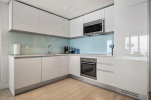 a kitchen with white cabinets and a microwave at NEW! 34th FL High Rise, PRIME Location, Downtown Near Stampede & Saddledome, FREE Wine & More! in Calgary