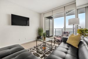 a living room with a couch and a tv at NEW! 34th FL High Rise, PRIME Location, Downtown Near Stampede & Saddledome, FREE Wine & More! in Calgary