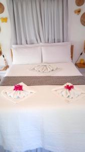 a white bed with red flowers on top of it at Casa de Mar Sagi in Baía Formosa