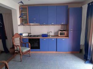 eine Küche mit blauen Schränken, einem Stuhl und einer Mikrowelle in der Unterkunft Vivenda Na Baia das Gatas in Baia das Gatas