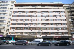 a large white building with cars parked in front of it at Nicolae Balcescu Dream House in Bucharest