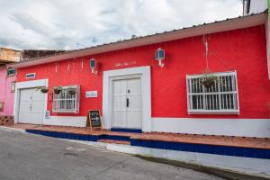 a red building with two white doors on a street at Hotel Casa David in Rivera