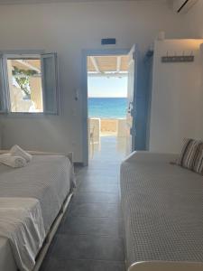 a bedroom with two beds and a view of the ocean at Palio Karnagio Παλιό Καρνάγιο in Koufonisia