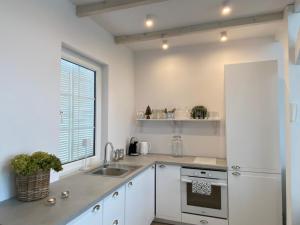 a kitchen with white cabinets and a sink and a window at Domek nad jeziorem całoroczny in Kikół
