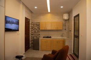 a kitchen with a tv on a wall next to a couch at Complexe Immobilier le Silence (CIS) in Lomé