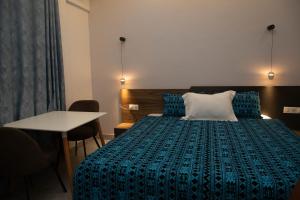 um quarto com uma cama com um edredão azul e uma mesa em Complexe Immobilier le Silence (CIS) em Lomé