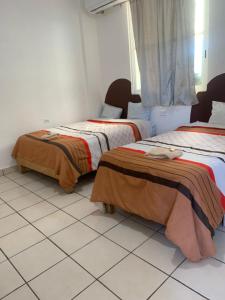 2 Betten in einem Zimmer mit Fliesenboden in der Unterkunft HOTEL PUERTO REAL in Paraíso