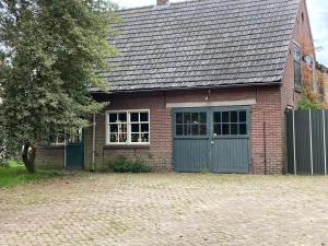 una casa de ladrillo con una puerta verde y un árbol en Het werkhuis, en Uden