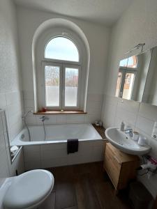 ein weißes Badezimmer mit einer Badewanne und einem Waschbecken in der Unterkunft Ferienwohnung zur Silbertanne in Ilsenburg