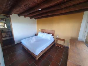 a bedroom with a white bed and a chair at Hotel Cariguá in Barichara