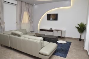 uma sala de estar com um sofá branco e uma televisão em Complexe Immobilier le Silence (CIS) em Lomé
