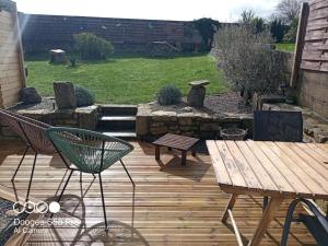 un patio con una terraza de madera con una mesa y un banco en Ty-Reviens, en Lanrivoaré