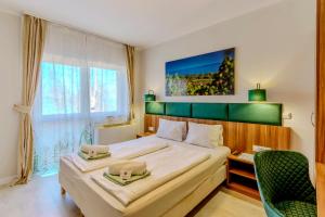 a bedroom with a large bed with a green headboard at Balaton Colors Beach Hotel in Siófok