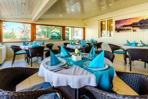 a restaurant with tables and chairs with blue napkins at Balaton Colors Beach Hotel in Siófok