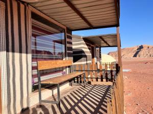 a wooden bench on the porch of a building in the desert at Rum luxury star in Wadi Rum