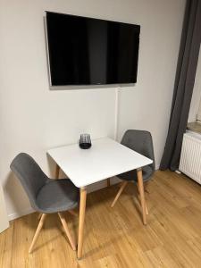 a white table with two chairs and a television on a wall at Modern living: Stylish one-bedroom flat in Hockenheim