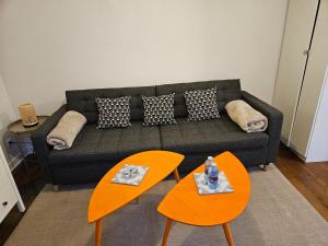 a living room with a couch and two orange tables at studio 11 Garcia stade de France in Saint-Denis