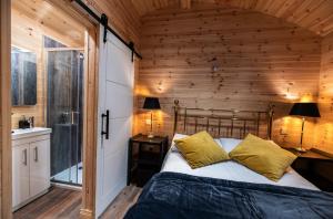 a bedroom with a wooden wall and a bed with yellow pillows at The Hen Harrier - 4 Person Luxury Glamping Cabin in Dungarvan