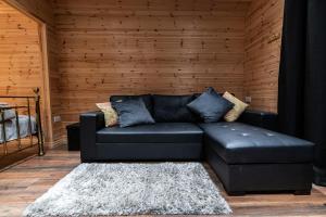 a black leather couch in a room with a wooden wall at The Hen Harrier - 4 Person Luxury Glamping Cabin in Dungarvan
