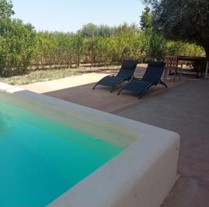2 sillas sentadas junto a una piscina en Casa independiente, a tres km de Moratalla, en Moratalla