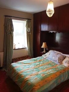 a bedroom with a bed and a window and a chandelier at Hardwood Hall or Kiltubber House in Kinnegad +20 photos