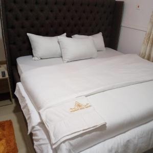 a bed with white sheets and white pillows at Mid Way Best Hotel in Lagos