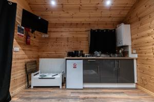 a kitchen with a refrigerator in a room with wooden walls at The Hen Harrier - 4 Person Luxury Glamping Cabin in Dungarvan