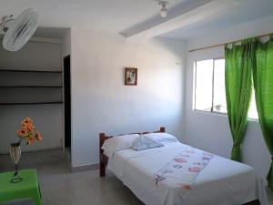 1 dormitorio con 1 cama con cortina verde y ventana en Hostal Adrimar, en Bahía Solano