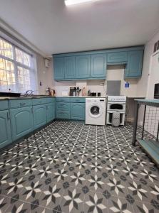 cocina con armarios azules y suelo de baldosa blanco y negro en London E2 Rooms en Londres