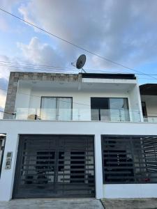 Biały budynek z dwoma drzwiami garażowymi i satelitą w obiekcie Casa En Leticia w mieście Leticia