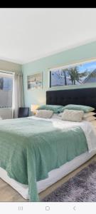 ein Schlafzimmer mit einem großen Bett und einer grünen Decke in der Unterkunft Three bedrooms two bathrooms ground floor only not the whole house in Mount Maunganui