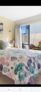 1 dormitorio con 1 cama con colcha de flores en Three bedrooms two bathrooms ground floor only not the whole house, en Mount Maunganui