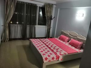 a bedroom with a bed with a red and white comforter at BleVaMa Ocean View Home in Dar es Salaam
