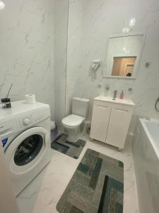 een badkamer met een wasmachine en een toilet bij Apartaments COSTA ЖК Тандау in Astana