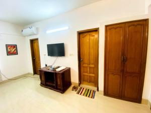 Habitación con TV y 2 puertas de madera. en Gulshan 1-Cozy Private Attached bath Room Ac Tv & Netflix, en Dhaka