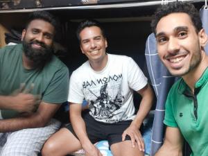 trois hommes assis à l'arrière d'une camionnette dans l'établissement White Moon Men's Hostel, à Dubaï
